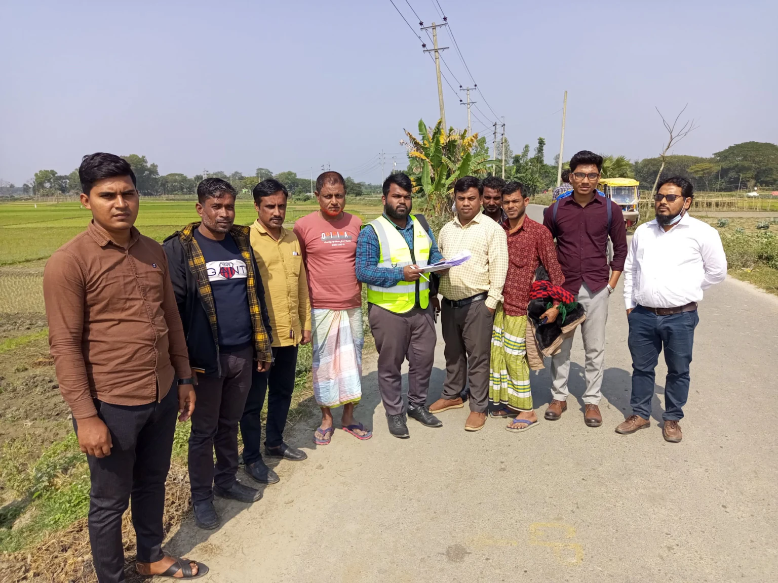 Environmental field team and site representatives together beside a rural road, with documents being reviewed